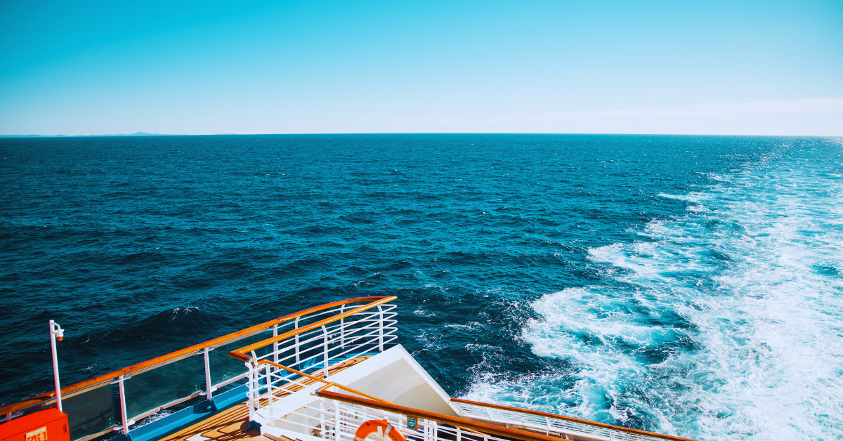 Ship on the ocean with blue sky and white trail