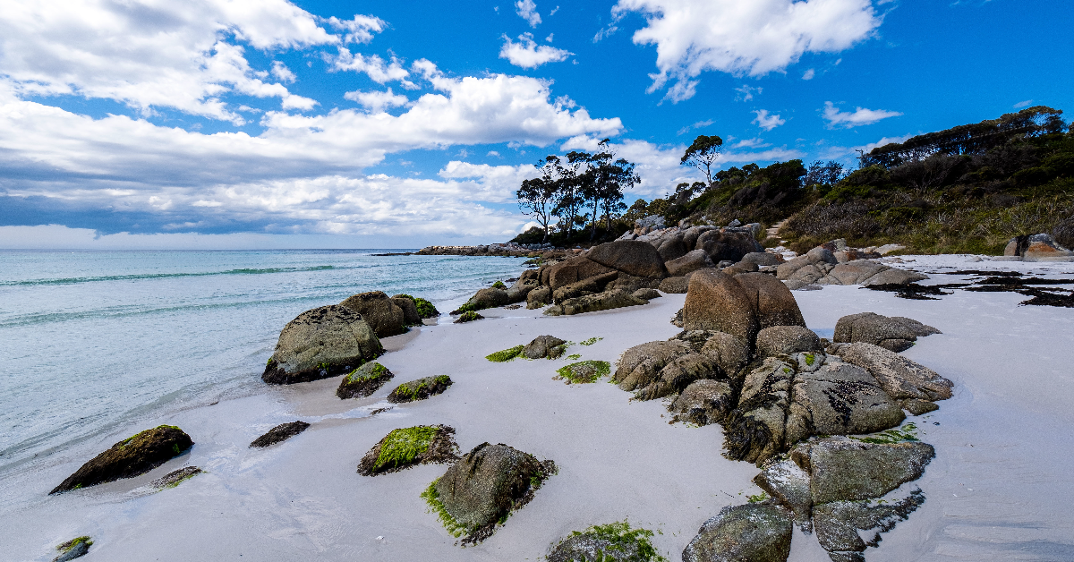 Rocky beach with white sand and blue sky
