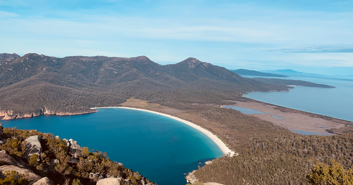 Beach with blue water and hills.