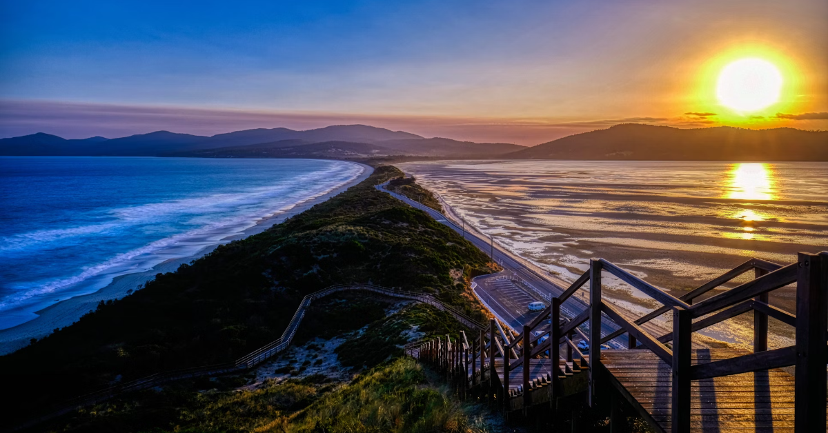 Sunset view over coastal walkway with ocean and calm waters.
